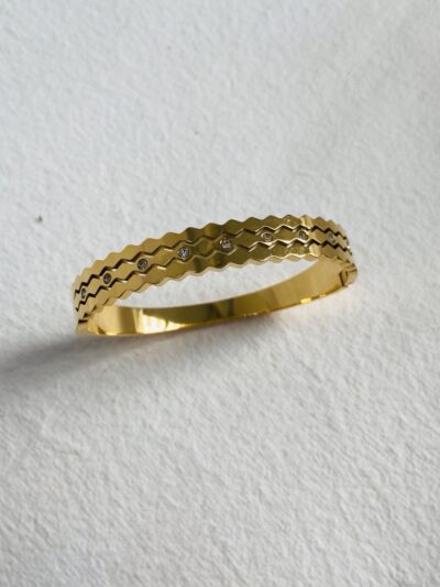 Stylish gold bangle with a unique zigzag design and diamond accents.